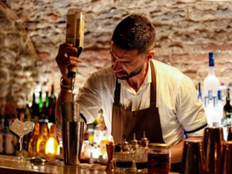 Een professionele bartender schenkt geconcentreerd een drankje in een cocktailshaker.