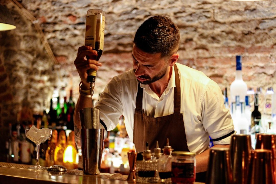 Een professionele bartender schenkt geconcentreerd een drankje in een cocktailshaker.