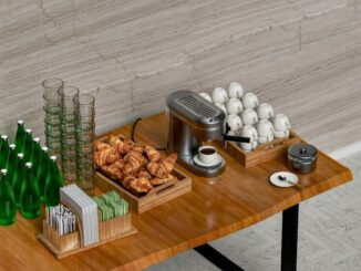 Koffiecorner met espressomachine, kopjes, glazen, water en croissants