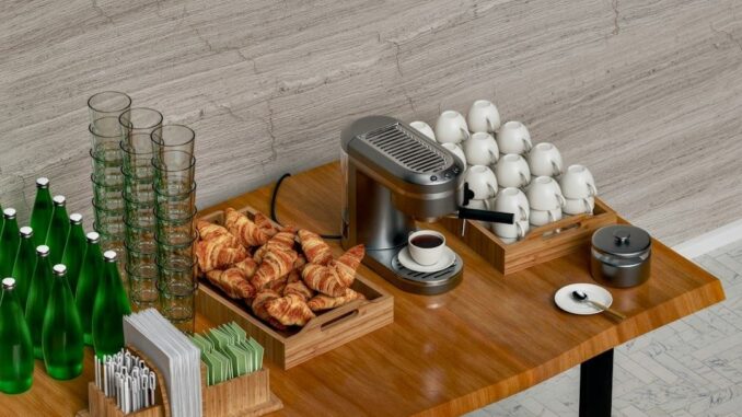 Koffiecorner met espressomachine, kopjes, glazen, water en croissants